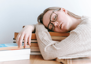 Femme qui s'est endormie sur une pile de livre 
